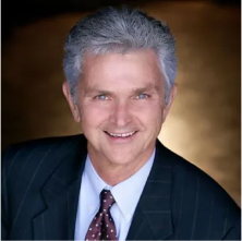 Brad Harper, Advisory Board Member at Lukrom, smiling in a professional suit and tie with a dark background