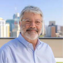 Tim Sprague, Advisory Board Member at Lukrom, smiling with a cityscape in the background